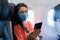 A girl in a medical mask on her face during a flight in the cabin. Air travel during a pandemic