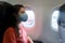 A girl in a medical mask on her face during a flight in the cabin. Air travel during a pandemic
