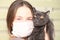 Girl medical mask on her face is holding British cat breed.toxoplasmosis protection against cat infection for humans