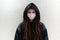 Girl in a medical mask in a hood against a white wall