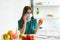 Girl in medical mask talking on smartphone and holding tomato at table with fruits, vegetables