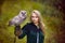 Girl in medieval dress is holding an owl on her arm