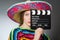 The girl in mexican vivid poncho holding clapboard