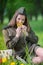 Girl in military uniform sits in a field on grass holding a bouquet