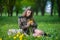 Girl in military uniform sits in a field on grass holding a bouquet