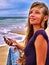 Girl with mobile phone sitting on sand near sea.