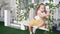 Girl model yellow skirt gets on a wicker swing