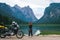 Girl motobiker in protective turtle jacket stands on the beach with tourer motorcycle. Extreme travel vacation, motorcyclist