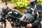 Girl motorcyclist holds a protective helmet in her hands on the background of a blurred motorcycle