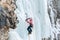 Girl mountaineer climbing a frozen waterfall and smiling