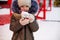 Girl with mug with snow, candy cane and inscription Merry and Bright in her hands outdoor in warm clothes in winter at festive