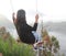 Girl on natural wooden swing enjoying beautiful morning mountain view.