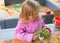 The girl in the nature at the table, playing with sand, plants a