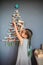 Girl near original Christmas tree made with branches, ecological toys, zero waste holidays