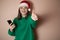 a girl in a New Year\\\'s hat is talking on the phone on a plain background, holding a phone in her hand, ordering dinner, the