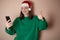 a girl in a New Year\\\'s hat is talking on the phone on a plain background, holding a phone in her hand, ordering dinner, the