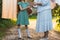 Girl next to an elderly woman. granddaughter helps her grandmother. a girl in a green dress is holding clothespins for wet clothes