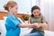 Girl nurse putting plaster on excited patient arm in hospital chamber