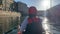 A girl with an oar floats on a red kayak, view from the back.