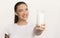 Girl Offering Glass Of Milk Standing Over White Studio Background