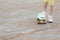 girl with one foot stands on the ground and the other with a foot on a skateboard against a background of asphalt