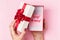 Girl opens a box with a gift on a pink background, top view. Concept no money for gifts