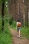 Girl with an orange backpack behind her back walking on a forest path.