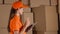 Girl in orange uniform counting storage boxes and using her tablet against brown cartons backround. Modern business