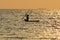 A girl with a paddle sails on a small boat on the sea waves in the evening darkness