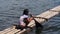 Girl paddles bamboo raft boat on lake shore