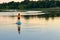 Girl paddling on SUP board on beautiful lake during sunset or sunrise, standing up paddle boarding morning adventure in Germany