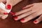 Girl paint nails with red nail polis on wooden table