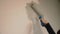 Girl paints the wall of the room with a roller at home repair painting