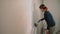 Girl paints the wall of the room with a roller at home repair painting