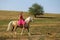 Girl on palomino ponny on meadow in summer afternoon