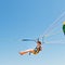 Girl parasailing on parachute in blue sky
