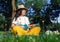 Girl in the park sitting on the grass plays the ukulele. Learning to play a four-string instrument. Relaxation in a public park.