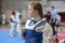 A girl participating in Taekwondo competitions in a blue protective vest on the background of Taekwondo competitions