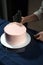 Girl Pastry Chef, makes a wedding cake with his own hands and squeezes the cream on the cake layers. A confectioner makes pink