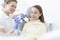 Girl patient looking at dentist brushing dentures at clinic