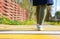 Girl pedestrian crossing the road on a yellow zebra,