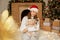 Girl with Pekingese dog on background of Christmas decorations and fireplace, woman with puppy sitting on floor on soft carpet,