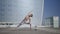 Girl performing yoga at street. Woman doing extended side angle pose at street