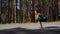 Girl performs a squat on an asphalt road in the forest. Beautiful curly sporty girl doing fitness outdoor at summer day