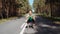 Girl performs a squat on an asphalt road in the forest. Beautiful curly sporty girl doing fitness outdoor at summer day