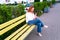 Girl with phone and coffee sits on the bench in the empty park