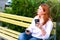 Girl with phone and coffee sits on the bench in the empty park