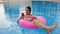 Girl photographed on cell phone Lying on pink inflatable ring in pool at summer resort
