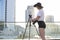 Girl-photographer with a camera and a tripod against the background of the city, she photographs the sunset, a woman getting ready
