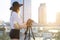 Girl photographer with a camera and a tripod on a background of the city, she photographs at sunset, a woman shoots a video